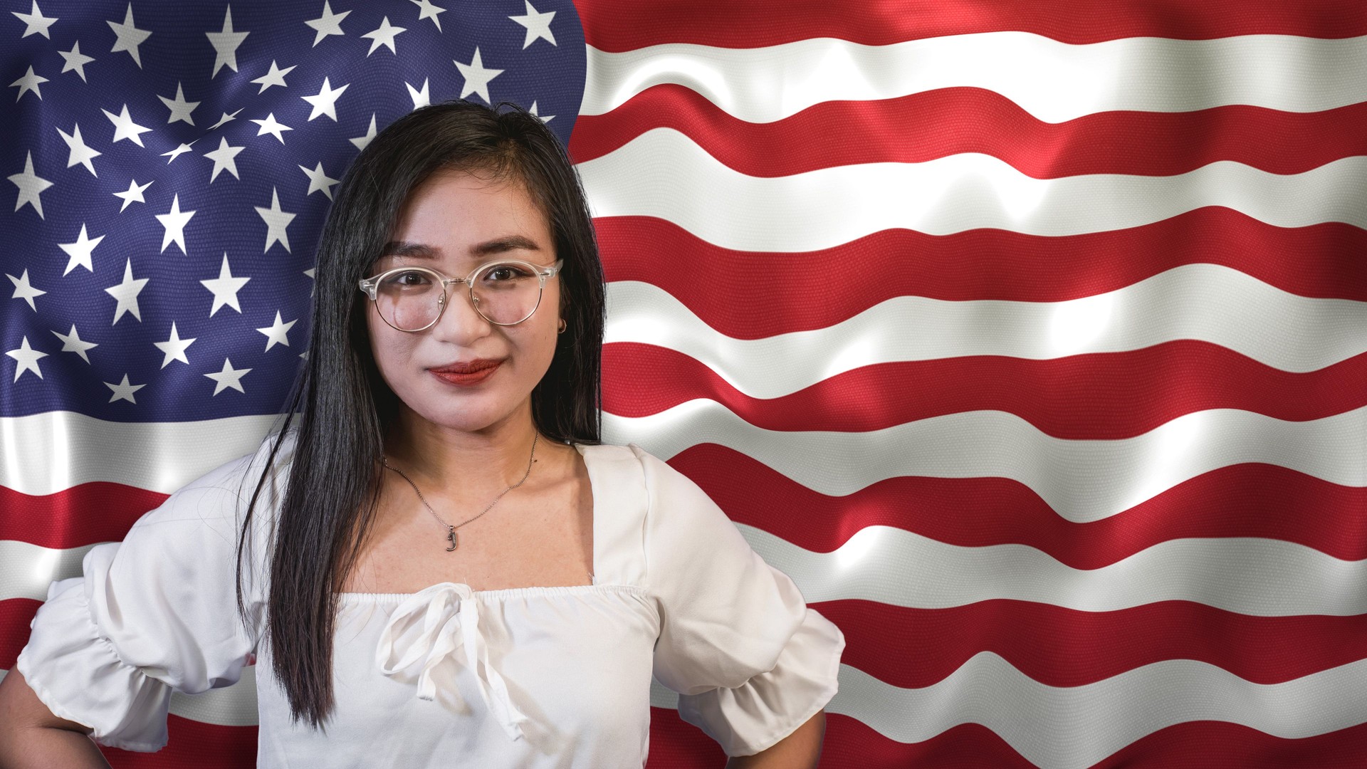 A proud young Asian American woman, in front of a waving US flag.