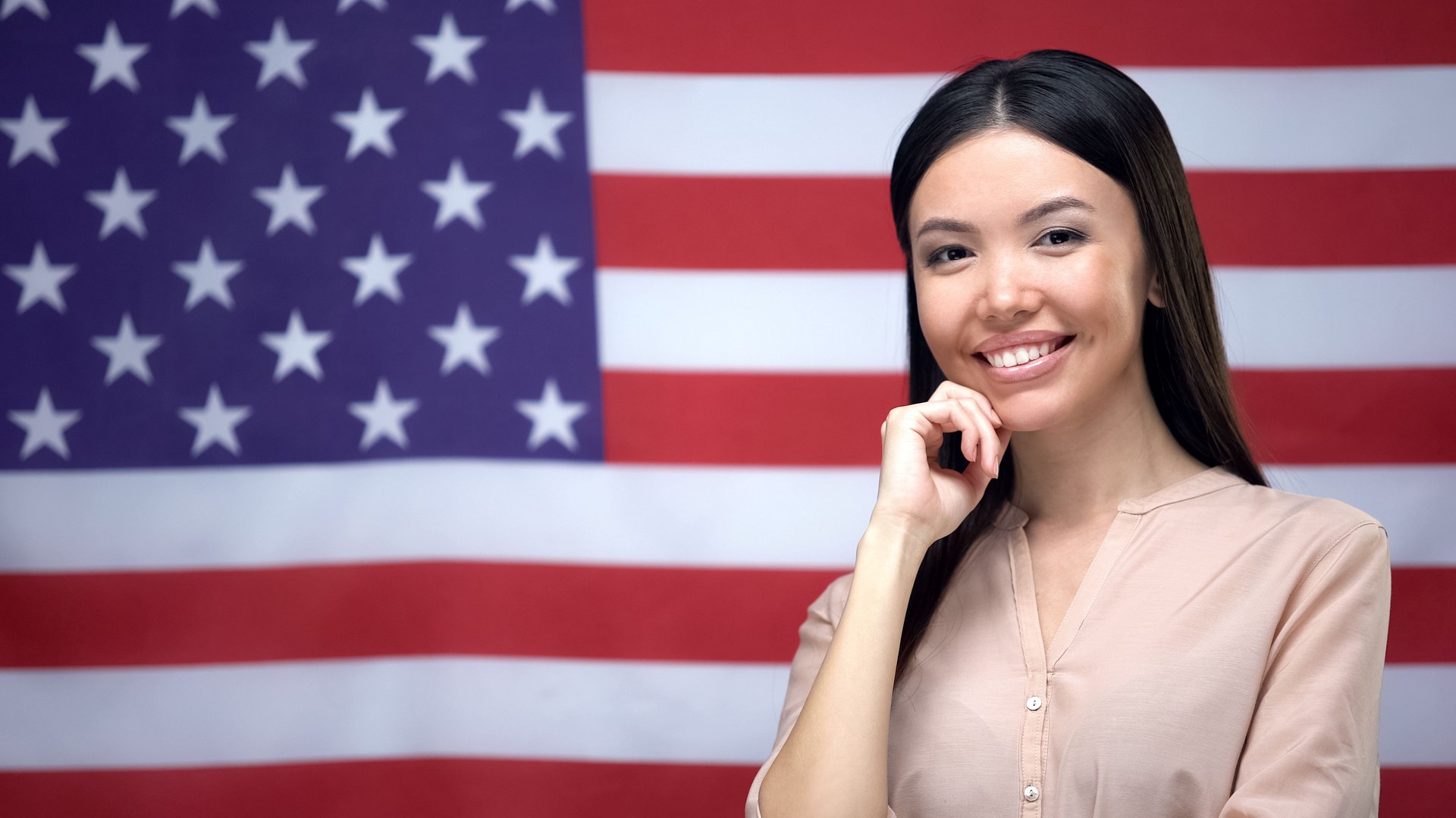Positive Asian woman standing against USA flag background, independence day