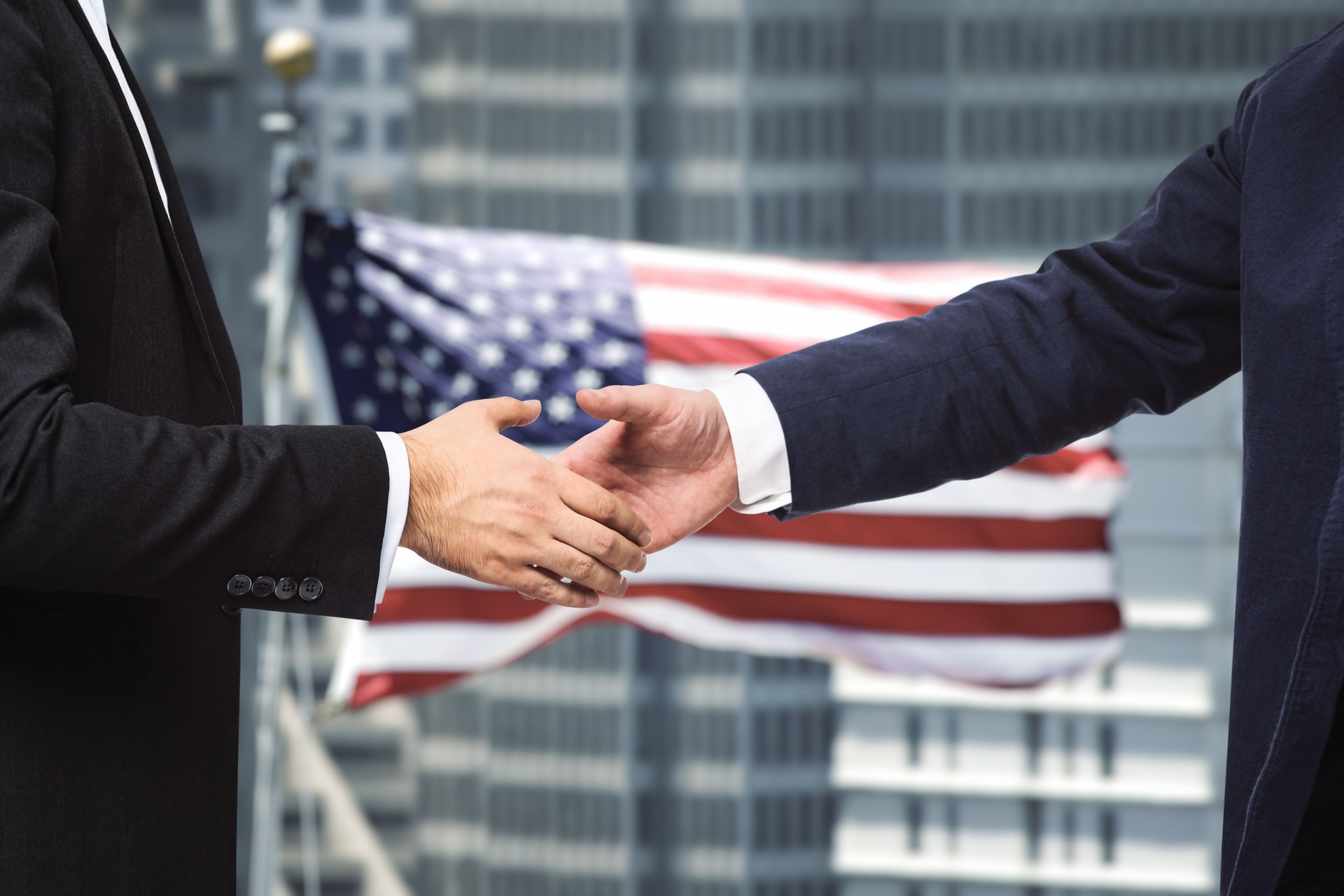 Handshake of two businessmen on the background of USA flag, partnership concept, close up