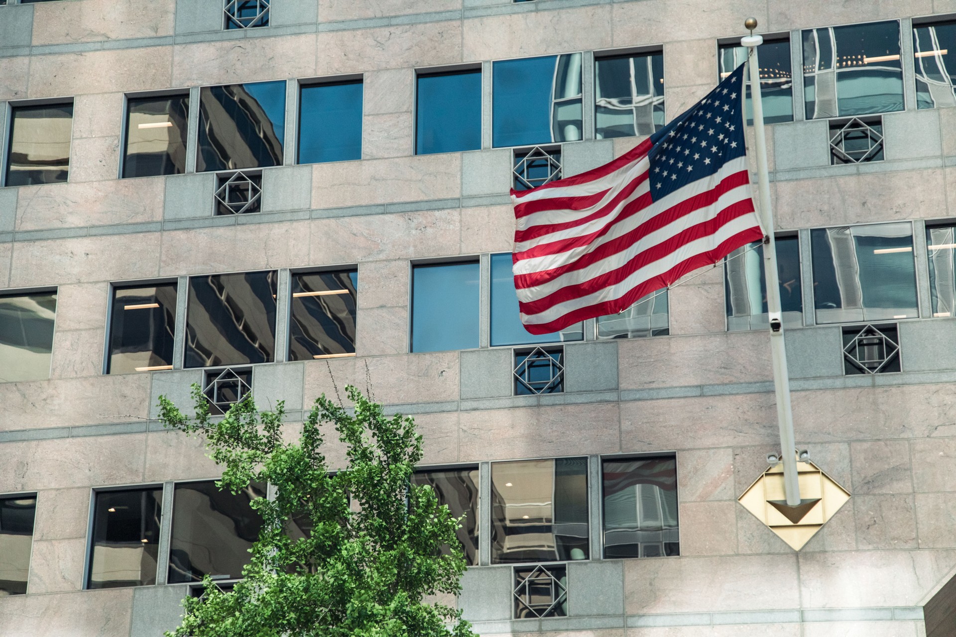 American flag proudly displays in front of a modern building in Washington DC during daylight