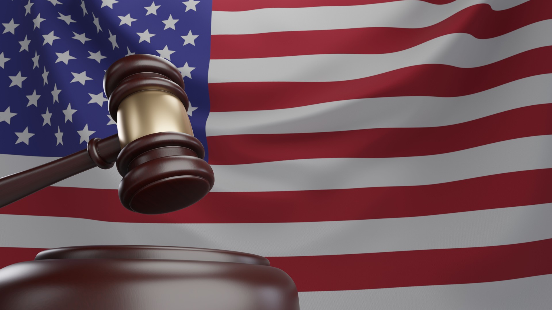 3d rendering of wooden court gavel, or auction hammer, with United States of America flag in the background.